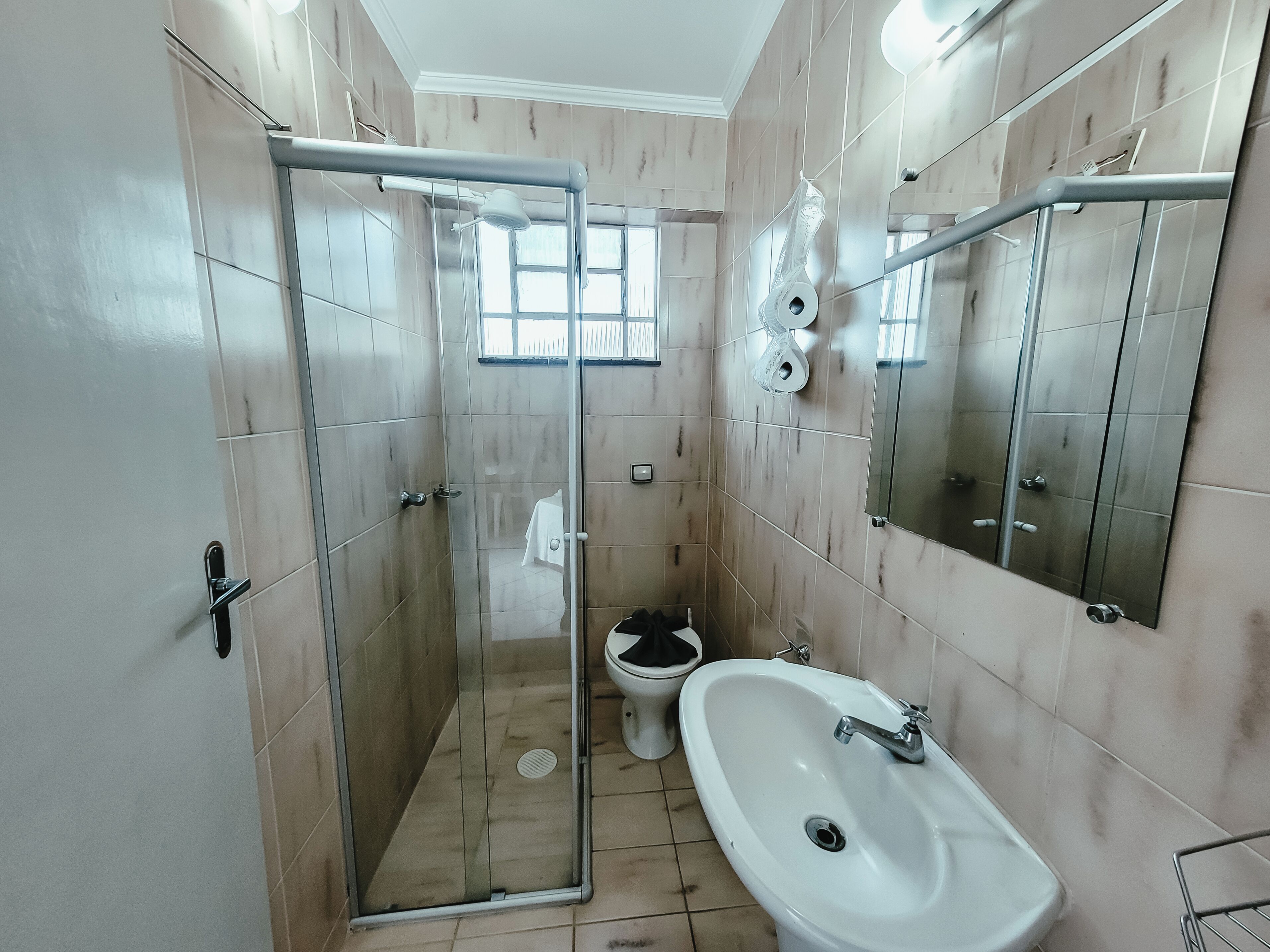 Un baño con ducha de mampara de vidrio, inodoro y lavamanos.