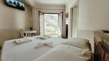 A hotel room with a bed, a desk, a TV, and a view of the outside.