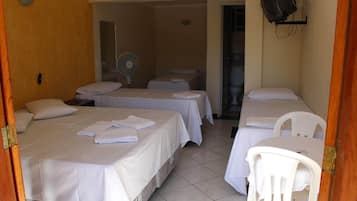 A hotel room with two beds, a fan, a TV, and a small table.