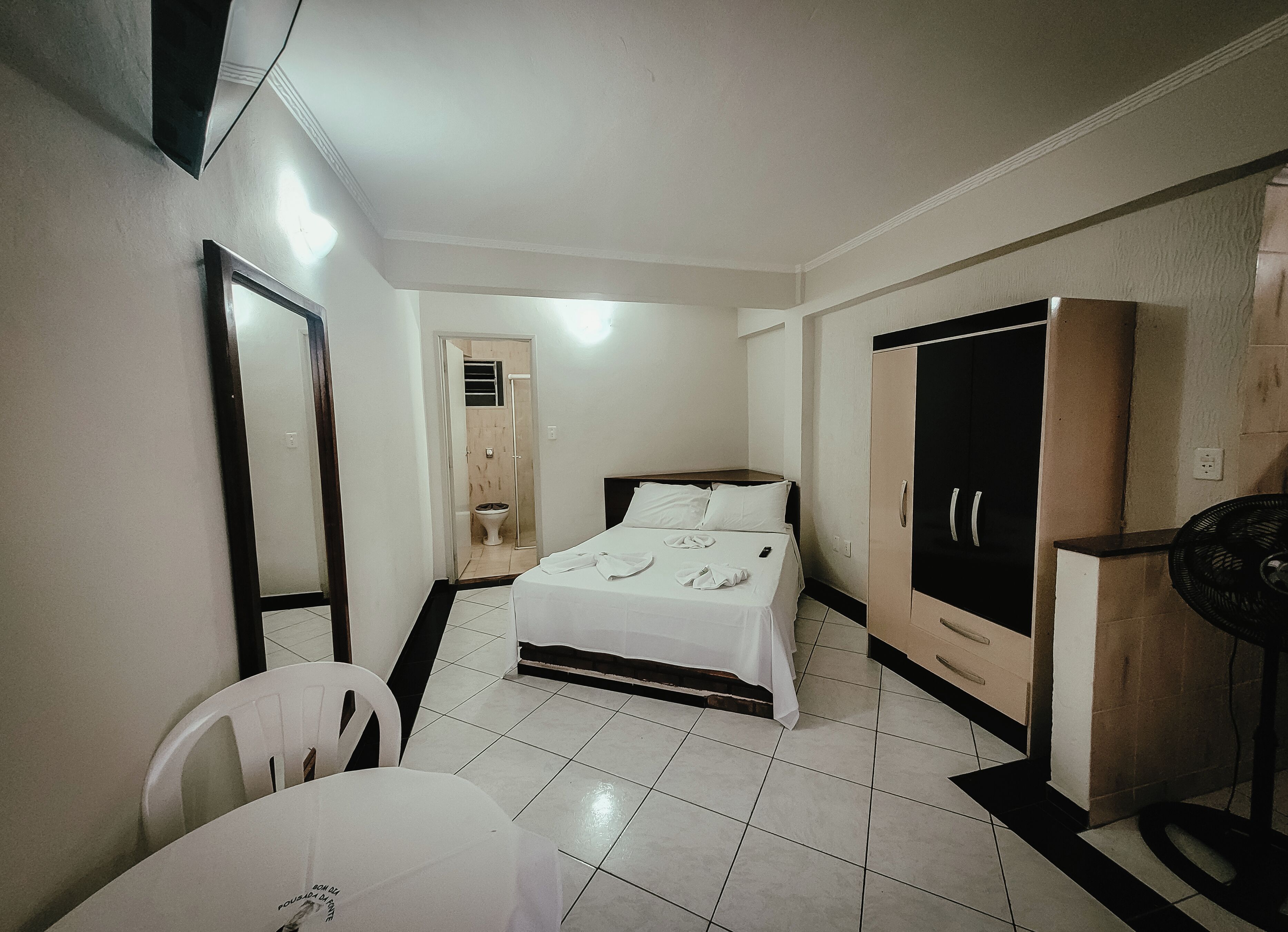 Una habitación de hotel con una cama, un armario, un espejo, una silla y una mesa.