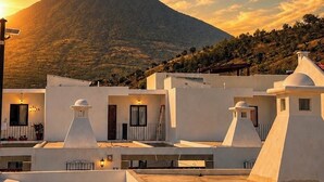 Un quartiere residenziale con edifici bianchi, una montagna sullo sfondo e un cielo al tramonto.