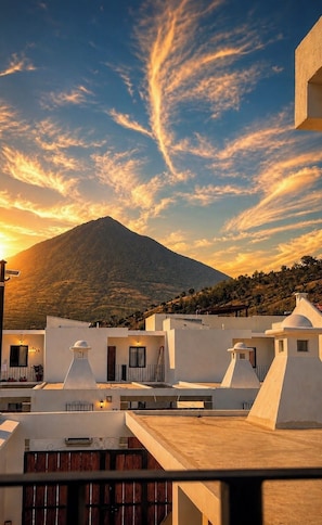 A residential area with white buildings, a mountain in the background, and a sunset sky. - Volcano Views Near Antigua! 3BR Retreat w/ Main-Floor Bedrooms (ciudad vieja)