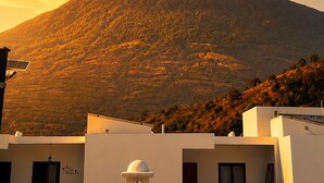 Una montagna con cielo sereno e un edificio in primo piano dotato di pannelli solari.