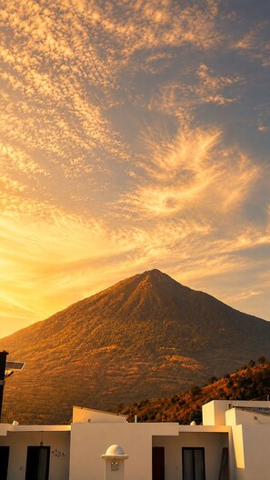 A mountain with a clear sky and a building with solar panels in the foreground. - Volcano Views Near Antigua! 3BR Retreat w/ Main-Floor Bedrooms (ciudad vieja)
