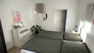 Ein Schlafzimmer mit Bett, Nachttischen, einem Spiegel und einer Tür.