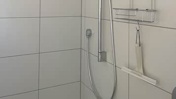 Eine Dusche mit einer Handbrause, einem Wandarmaturen und einem Metallregal mit Haken.