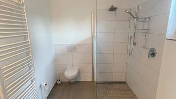 Une salle de bain avec douche, toilettes et radiateur.