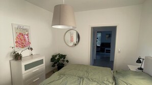 A bedroom with a bed, a dresser, a mirror, and a hanging lamp.