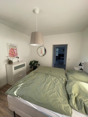 A bedroom with a bed, a dresser, a mirror, and a hanging lamp.