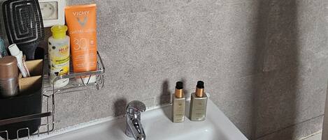 A bathroom with a white sink, a mirror, and toiletries.