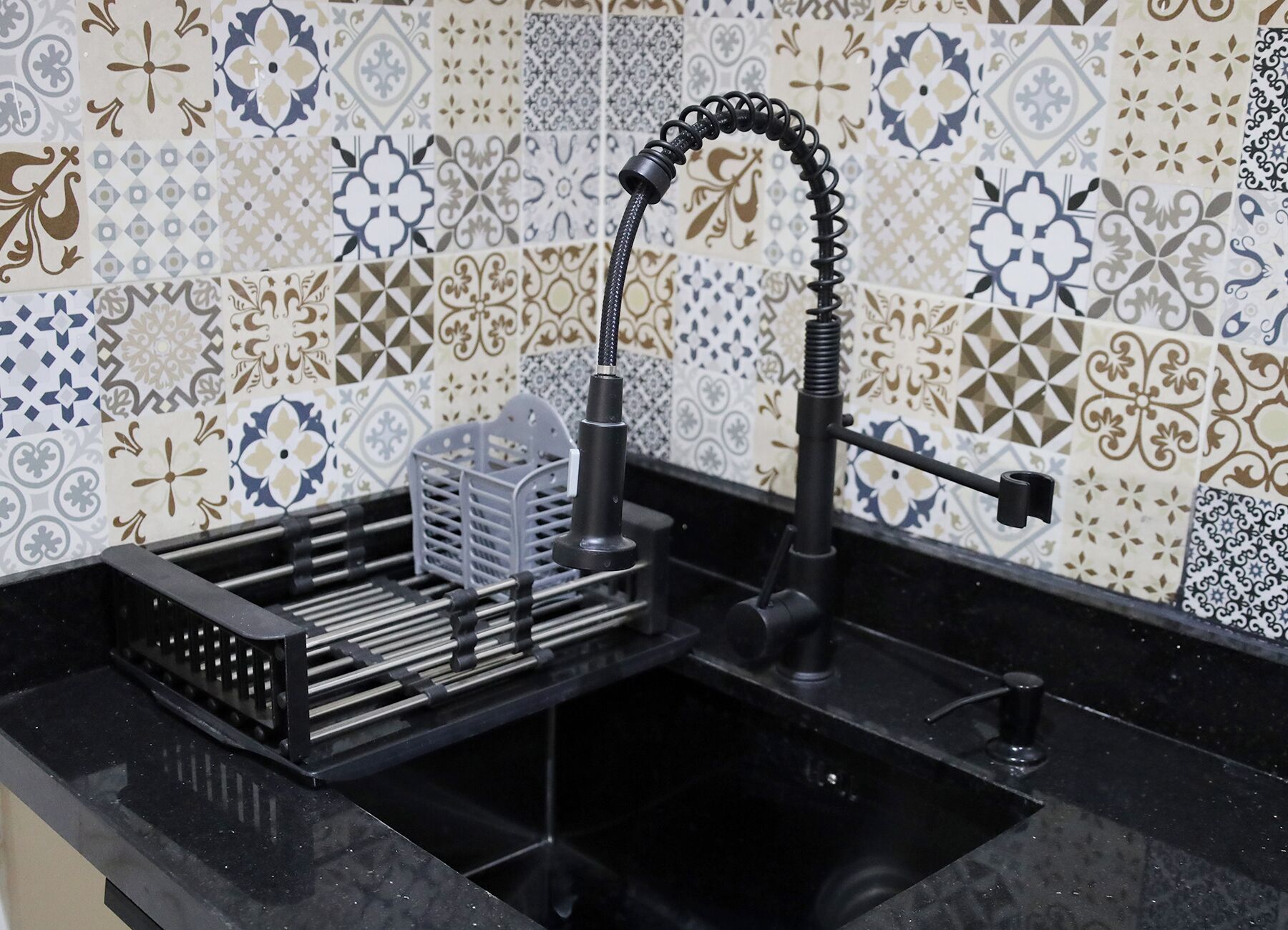 Een keuken met een spoelbak, een kraan en een rek met keukengerei.