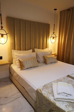 A neatly made bed with a headboard, two bedside lamps, and a folded towel on the bed.
