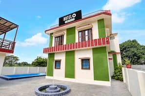 A hotel with a sign indicating it is serviced by Oyo. It features a two-story structure with a pool and a circular water feature in front. - Classic Nautiyal Home Stay (Vikasnagar)