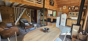 A wooden interior with a dining area, kitchen, and a staircase.