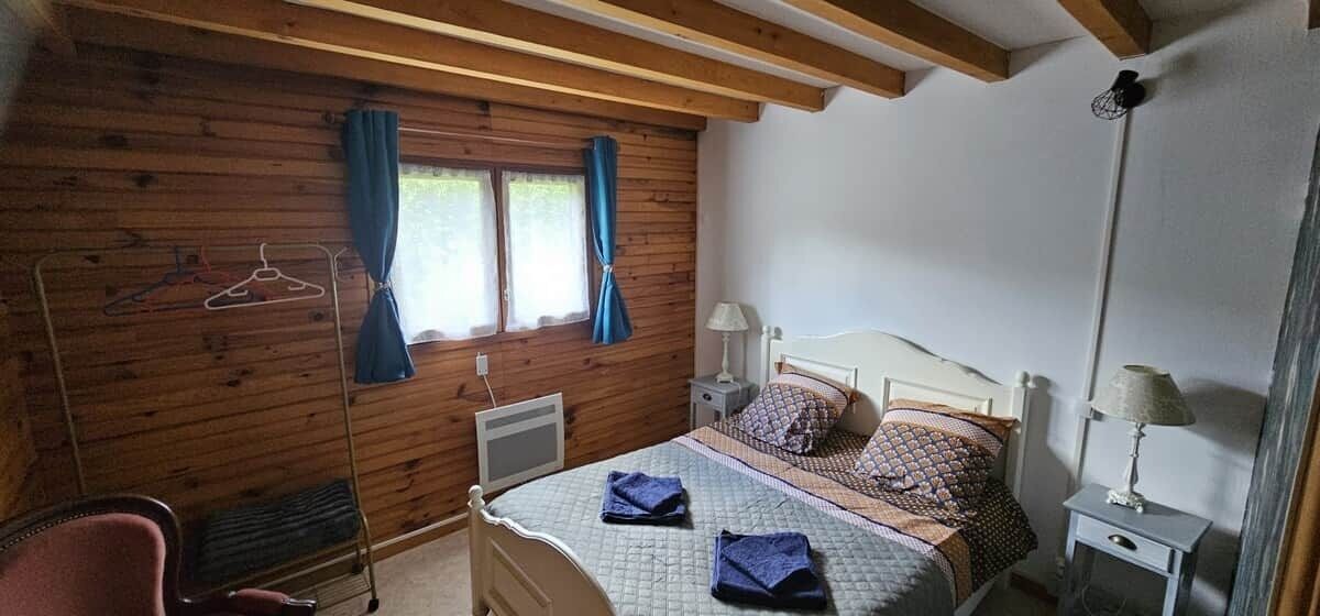 A bedroom with a bed, bedside tables, a chair, a heater, and a window with curtains.