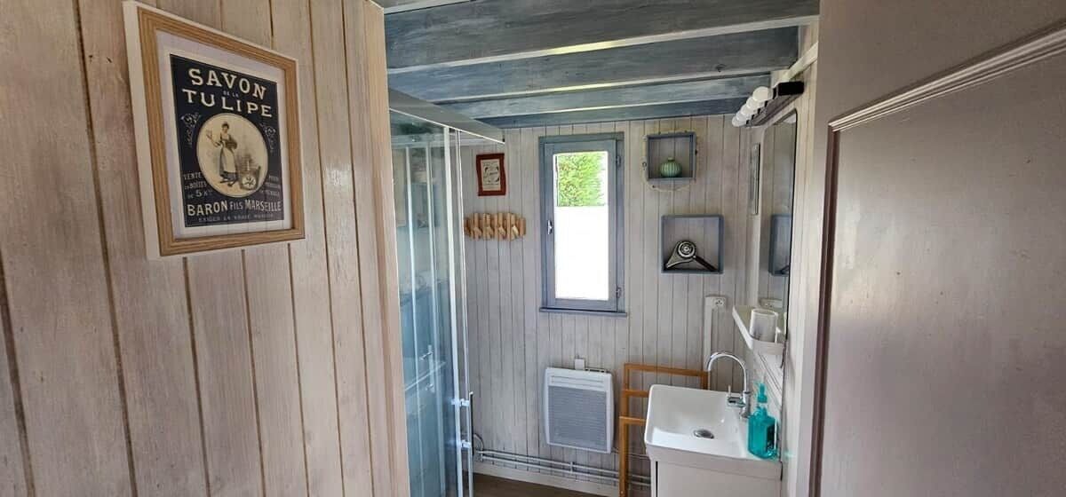 Een badkamer met een lijst rond een advertentie, een raam, een radiator en een wastafel.