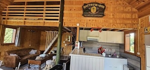 A wooden cabin interior with a kitchen area, a sofa, and a dining table.