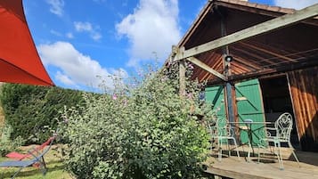 Un bâtiment en bois doté d’un espace extérieur abrité avec des sièges et d’une porte verte.