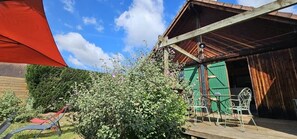 Un bâtiment en bois doté d’un espace extérieur abrité avec des sièges et d’une porte verte.