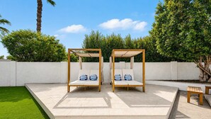 Two wooden swing beds with cushions, a white wall, and a small table in a garden setting. - NEW| The Fairmont @ Kierland | Pool, Spa & Daybeds (Scottsdale)