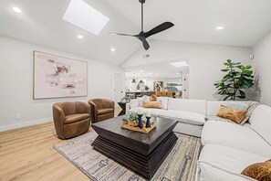 A modern living room with a white sofa, brown leather chairs, a dark coffee table, and a ceiling fan. - NEW| The Fairmont @ Kierland | Pool, Spa & Daybeds (Scottsdale)