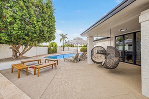 A pool area with a wooden bench, lounge chairs, and a hanging chair. - NEW| The Fairmont @ Kierland | Pool, Spa & Daybeds (Scottsdale)