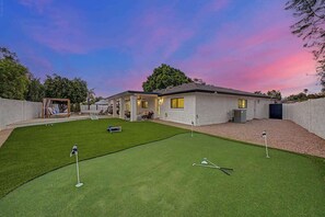 A residential property with a well-maintained lawn, a covered patio area, and a house with a visible chimney. - NEW| The Fairmont @ Kierland | Pool, Spa & Daybeds (Scottsdale)