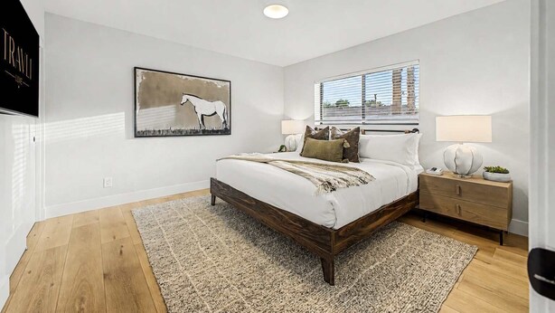 A bedroom with a large bed, a nightstand, a lamp, a window with blinds, and a wall-mounted artwork of a horse. - NEW| The Fairmont @ Kierland | Pool, Spa & Daybeds (Scottsdale)