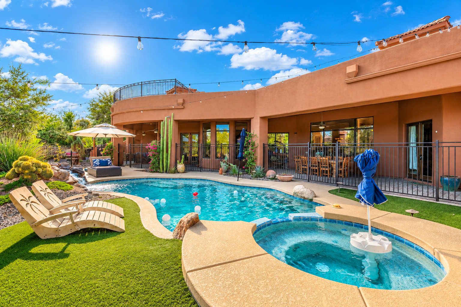A pool area with a hot tub, lounge chairs, and a patio with outdoor furniture.