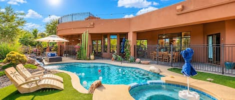 A pool area with a hot tub, lounge chairs, and a patio with outdoor furniture.