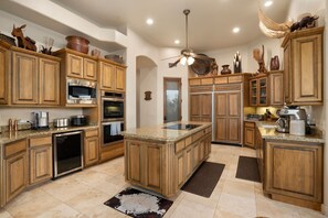 A kitchen with wooden cabinets, stainless steel appliances, and a central island. - Desert Vista Off-Road Experience|E-Dirt Bikes|Pool (Scottsdale)