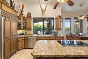 Eine moderne Küche mit Granit Arbeitsplatten, Holzschränken und einer großen Kücheninsel.