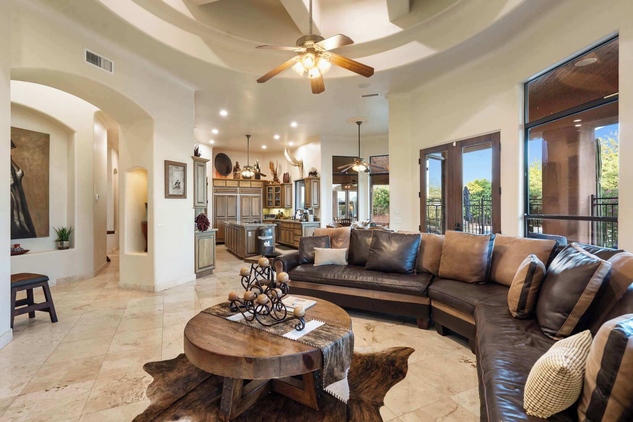 A spacious living area with a leather sofa, a round coffee table, and a ceiling fan.