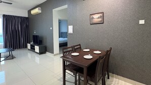 A modern dining area with a dark wooden table and chairs, a flat-screen TV, and a ceiling fan. - Spacious Stay at Danga Bay - Entire Unit (Johor Bahru)
