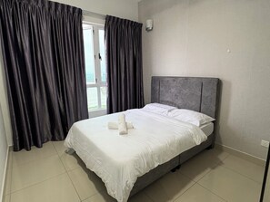 A hotel room with a bed, curtains, a window, and a wall-mounted light. - Spacious Stay at Danga Bay - Entire Unit (Johor Bahru)