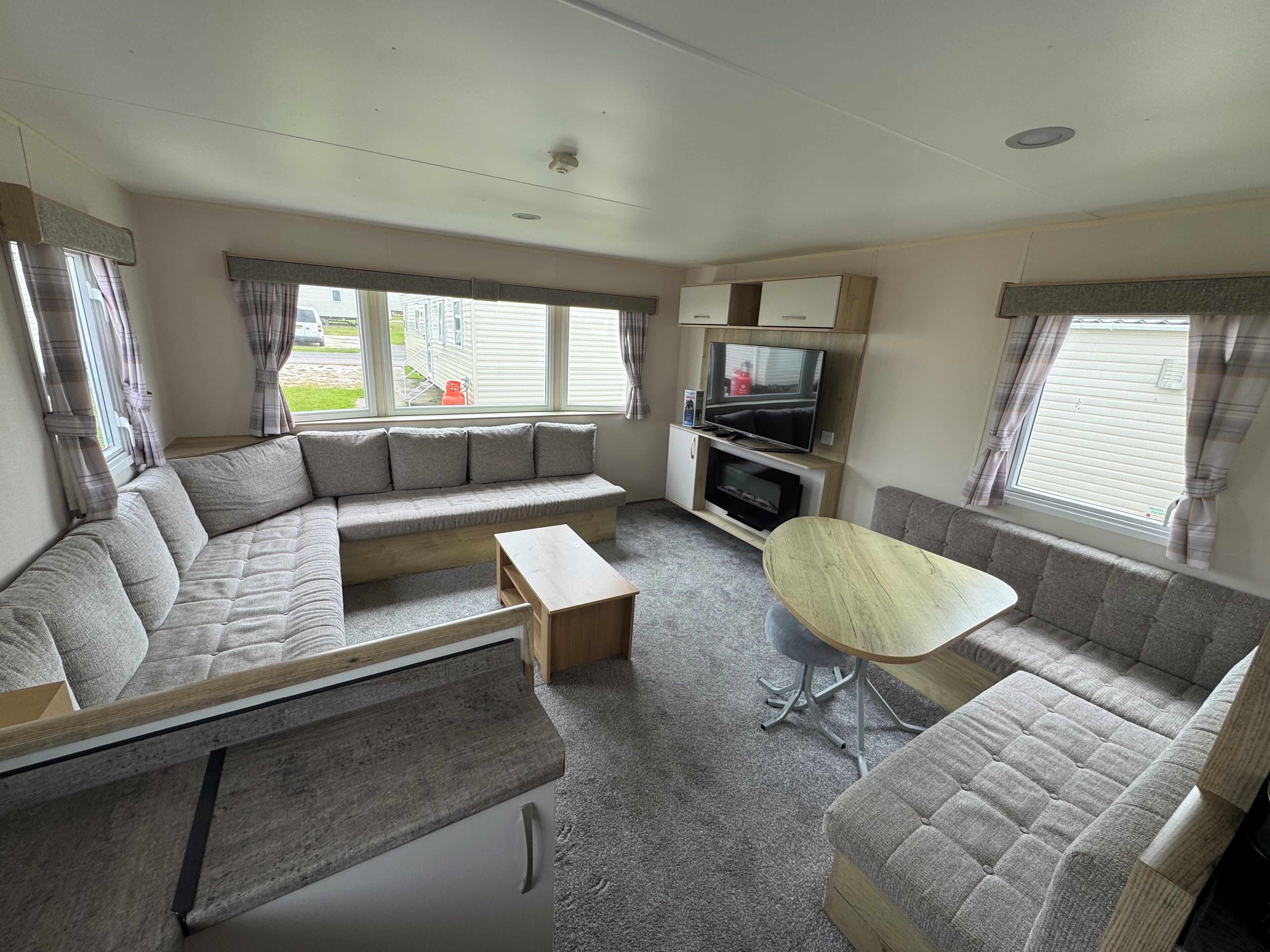 A compact living space with a sofa, a small table, a TV, and a window with curtains.