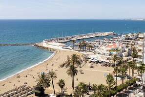 Eine Küstenstadt mit Strand, Hafen und Häusern mit Balkonen.