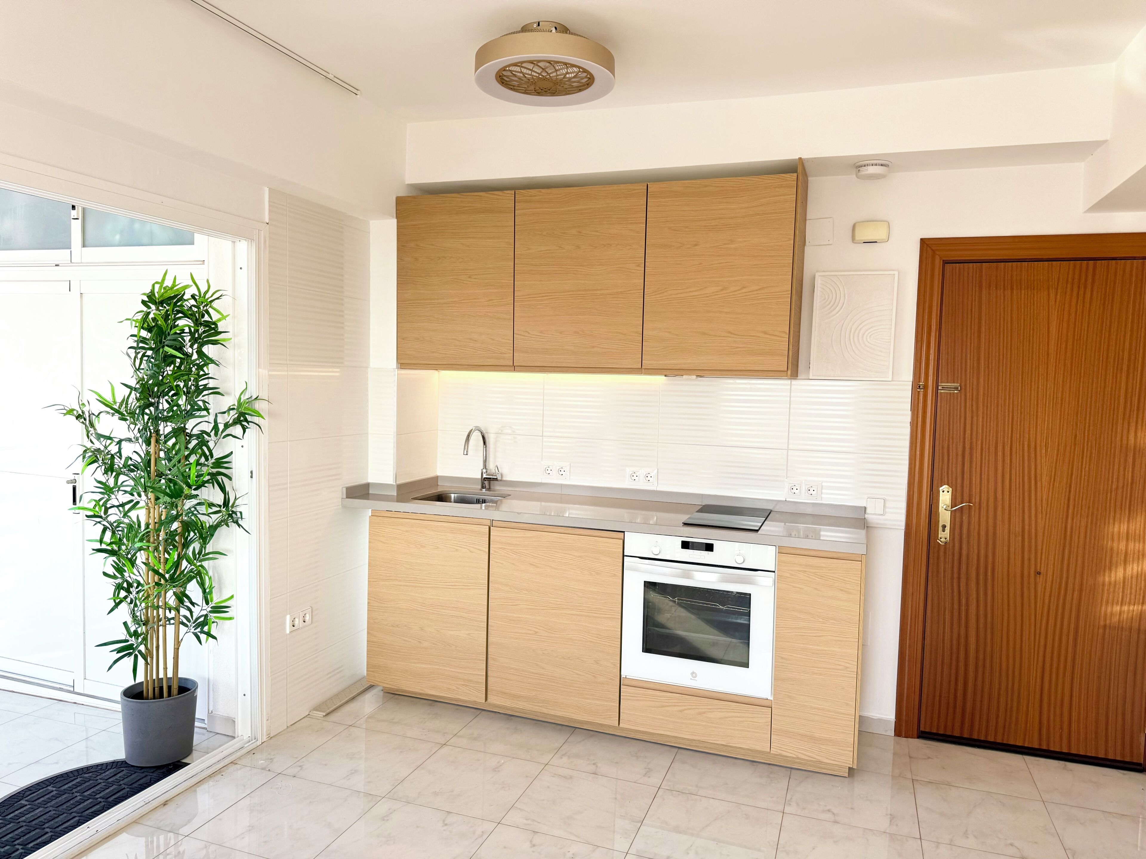 Una cocina moderna con armarios de madera, un lavamanos de acero inoxidable y un horno.