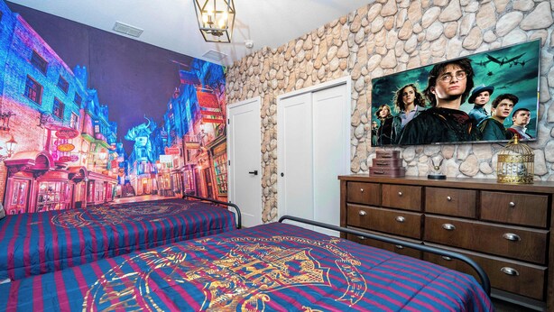 Une chambre avec un mur en pierre, une télévision, un lit recouvert d’une courtepointe aux couleurs vives et une commode.