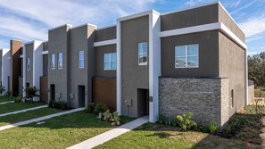 A modern apartment building with a uniform facade, multiple windows, and a well-maintained lawn. - Designer Disney Escape with Themed Rooms (Kissimmee)