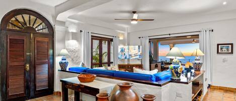 A spacious living area with a large window, a blue sofa, a wooden table, and a decorative vase.