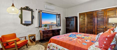 Un dormitorio con cama, una silla, cómoda, espejo y ventilador de techo.