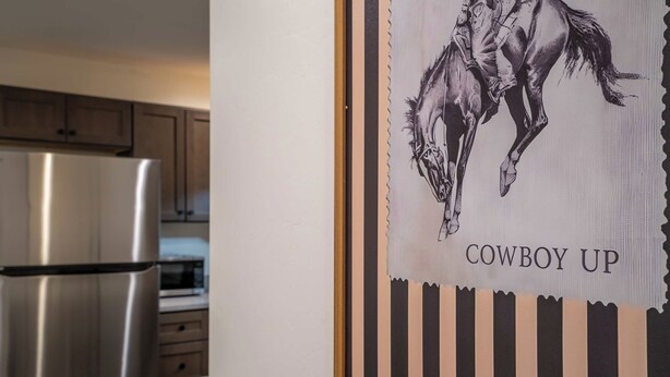 A kitchen with stainless steel appliances and a framed artwork depicting a horse with the text 'COWBOY UP'. - Iron Horse at Hoff & Co | Off 4th Ave (Tucson)