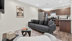 A modern living room with a grey sofa, a glass coffee table, and a small side table. - Iron Horse at Hoff & Co | Off 4th Ave (Tucson)