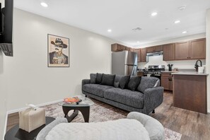A modern living room with a grey sofa, a glass coffee table, and a small side table. - Iron Horse at Hoff & Co | Off 4th Ave (Tucson)