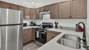 A modern kitchen with stainless steel appliances, wooden cabinets, and a built-in oven. - Iron Horse at Hoff & Co | Off 4th Ave (Tucson)