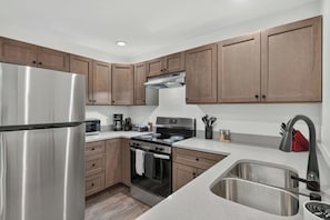 A modern kitchen with stainless steel appliances, wooden cabinets, and a built-in oven. - Iron Horse at Hoff & Co | Off 4th Ave (Tucson)