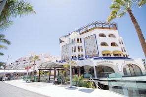A hotel with multiple balconies, a covered entrance, and palm trees. - Parque Santiago III 223 - One Bed (Arona)