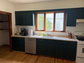 A kitchen with a dishwasher, a coffee maker, a sink, and a stove.