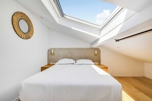 A bedroom with a skylight, a bed, a bedside table, and a wall-mounted lamp. - Spacious Apartment 2ch/6p - Boulogne-billancourt (Boulogne-Billancourt)